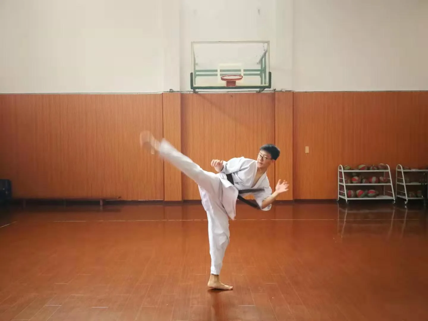 Yuchen Luo practising a high kick in a karate gi during an earlier training session.